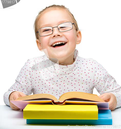 Image of Cute cheerful little girl reading book