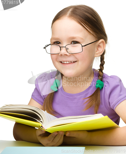 Image of Cute cheerful little girl reading book