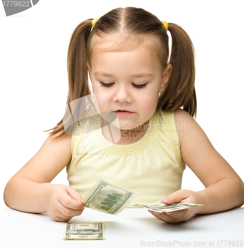 Image of Cute cheerful little girl is counting dollars
