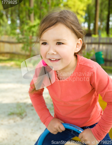 Image of Happy little girl is swinging on see-saw