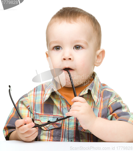 Image of Cute little child is biting glasses