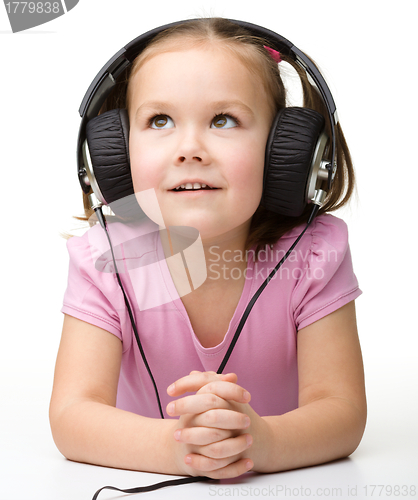 Image of Cute little girl enjoying music using headphones