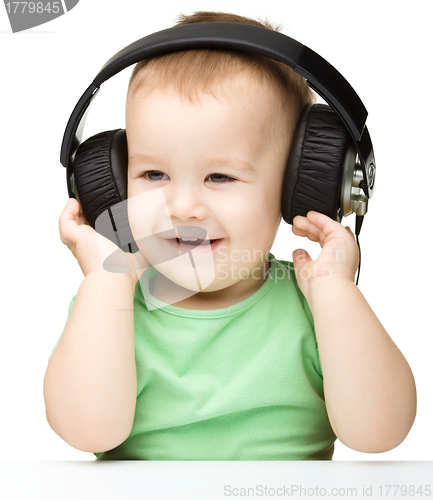 Image of Cute little boy enjoying music using headphones