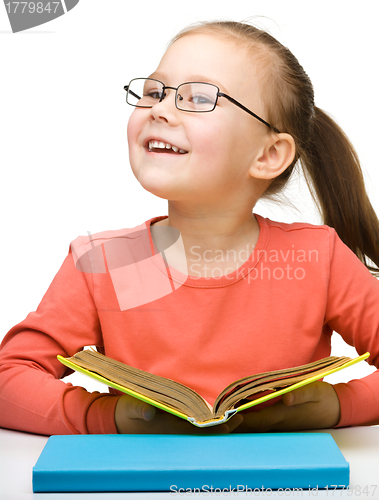 Image of Cute cheerful little girl reading book