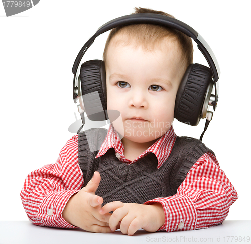 Image of Cute little boy enjoying music using headphones