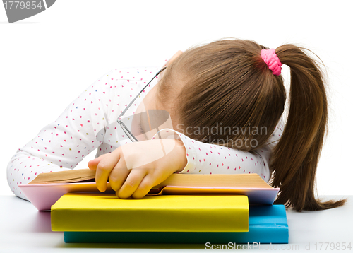 Image of Cute little girl is sleeping on a book