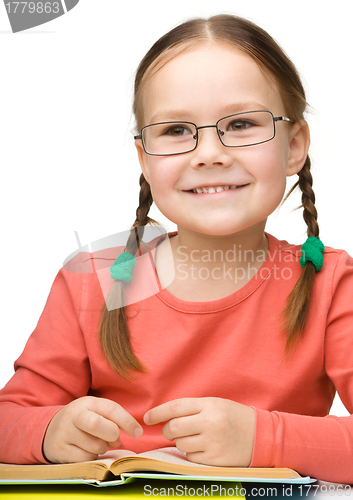 Image of Cute cheerful little girl reading book