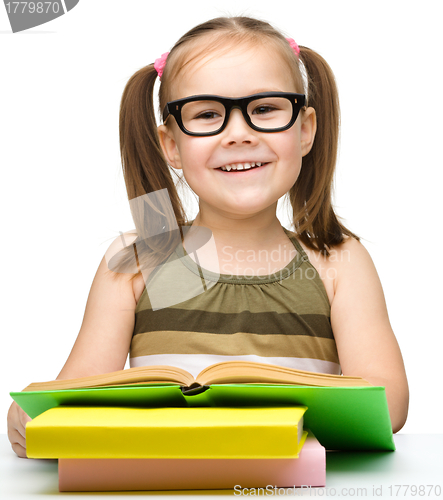 Image of Cute cheerful little girl reading book