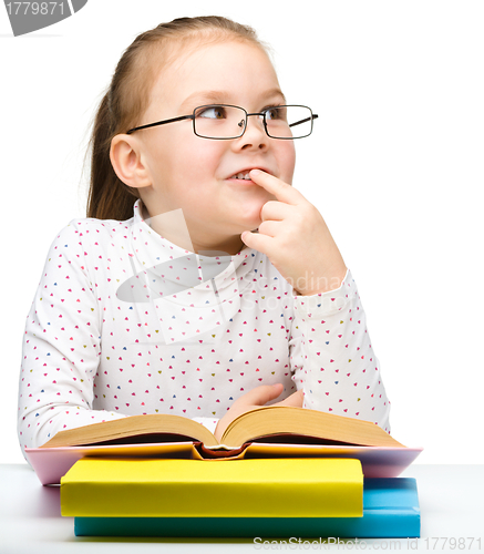 Image of Cute little girl is dreaming while reading book