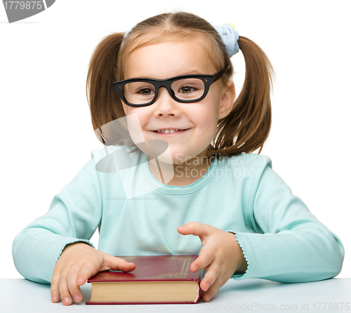Image of Happy little girl with book wearing black glasses