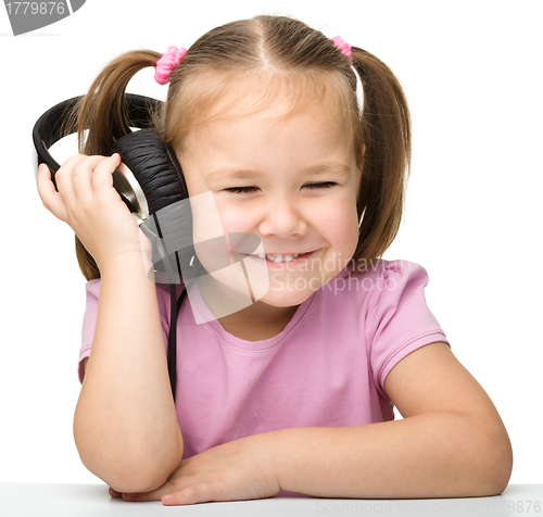 Image of Cute little girl enjoying music using headphones