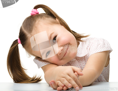 Image of Happy little girl sits at a table and smile