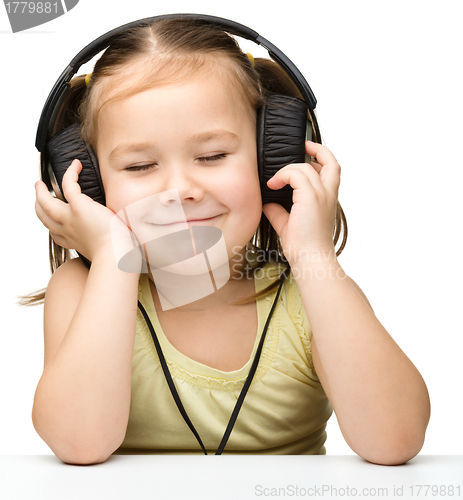 Image of Cute little girl enjoying music using headphones