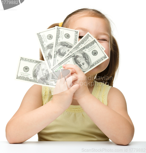 Image of Cute little girl is covering her eyes with dollars