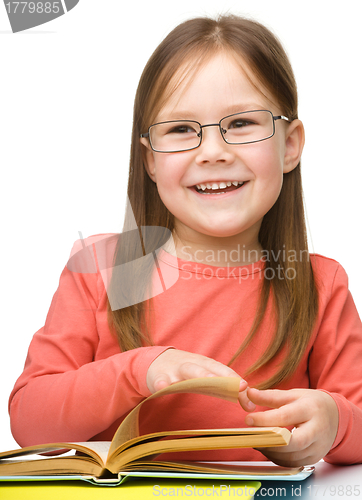 Image of Cute cheerful little girl reading book