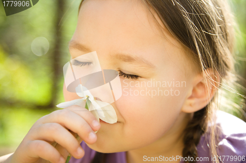 Image of Portrait of a cute little girl smelling flowers