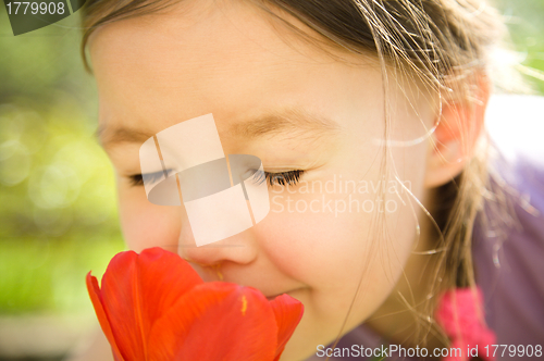 Image of Portrait of a cute little girl smelling flowers