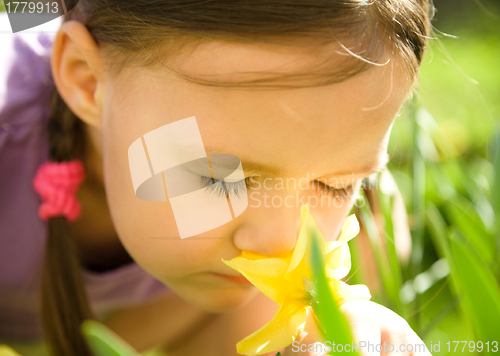 Image of Portrait of a cute little girl smelling flowers