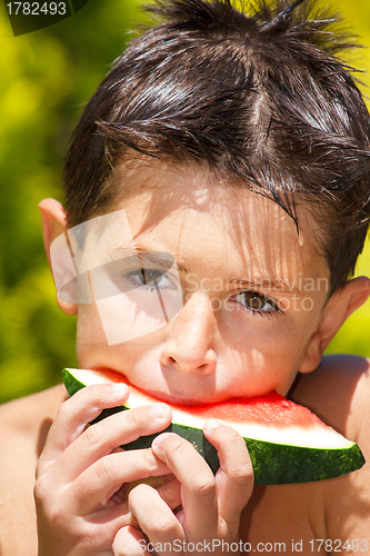 Image of wet boy with watermelon in the garden