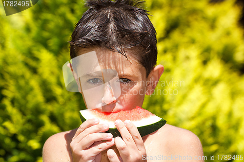 Image of wet boy with watermelon in the garden