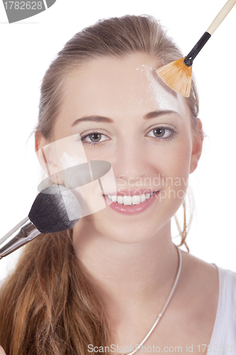 Image of young beautiful woman applying mineral powder 