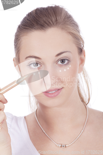 Image of young beautiful woman applying concealer on face