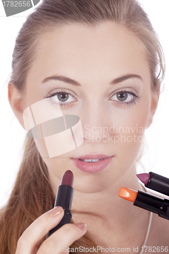 Image of young beautiful woman applying colored lipstick 