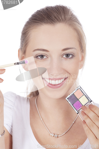 Image of young beautiful woman applying eyeshadow on eyes