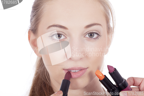 Image of young beautiful woman applying colored lipstick 