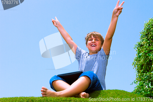 Image of Happy boy on the grass using his tablet computer