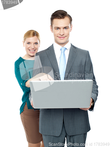 Image of Woman pointing into laptop while guy holding it