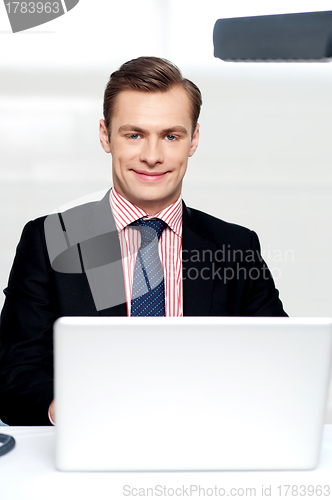 Image of Attractive smiling man operating a laptop