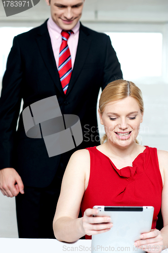 Image of Boss operating tablet pc and assistant looking