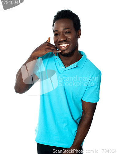 Image of Smiling young man showing calling gesture