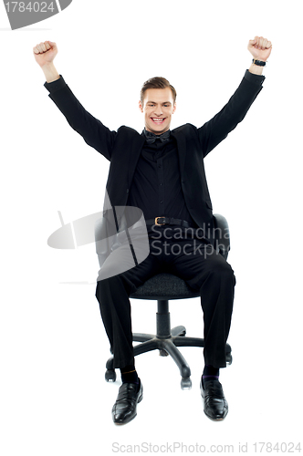 Image of Excited young man sitting on chair