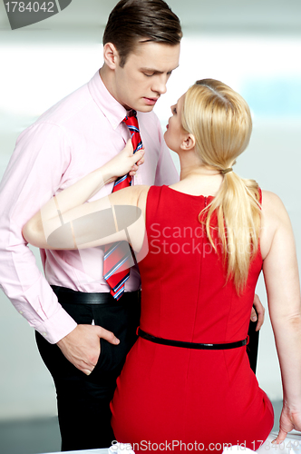 Image of Woman pulling man from his tie. Feeling naughty