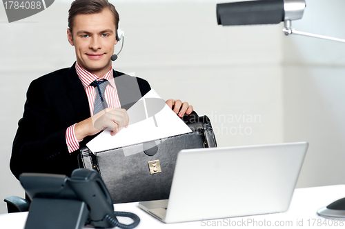 Image of Male call centre executive arranging paper works