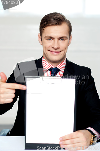 Image of Smiling man pointing towards blank clipboard