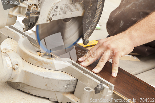 Image of Contractor Using Circular Saw Cutting of New Laminate Flooring