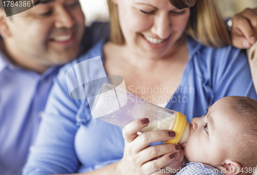 Image of Happy Mixed Race Couple Bottle Feeding Their Son