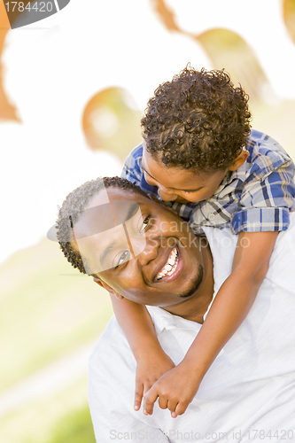 Image of Mixed Race Father and Son Playing Piggyback in Park