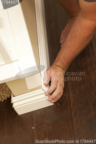 Image of Contractor Fitting New Baseboard to Wall and New Laminate Floori