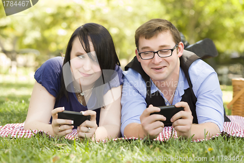 Image of Young Couple at Park Texting Together