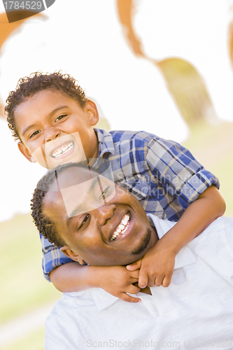 Image of Mixed Race Father and Son Playing Piggyback in Park