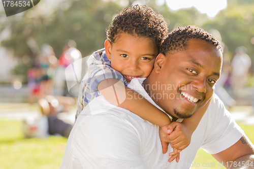 Image of Mixed Race Father and Son Playing Piggyback in Park