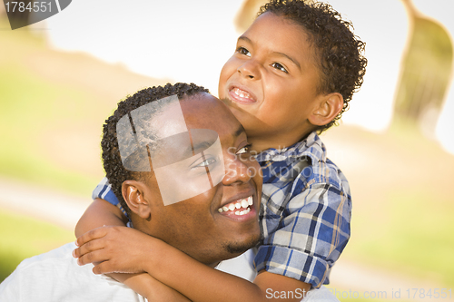 Image of Mixed Race Father and Son Playing Piggyback in Park