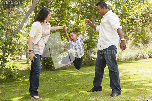 Image of Hispanic Mother and Father Swinging Son in the Park