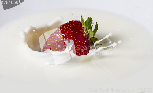 Image of strawberry falling in milk