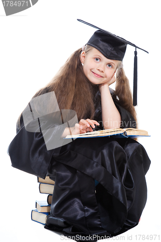 Image of girl in black academic cap and gown reading big blue book