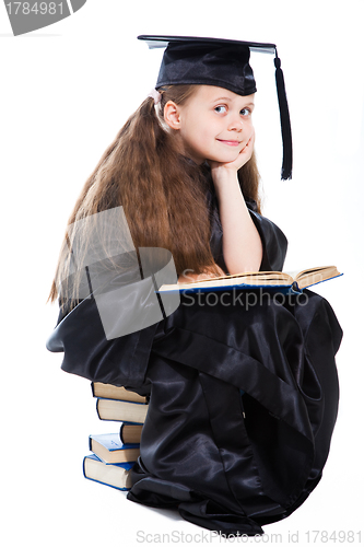 Image of girl in black academic cap and gown reading big blue book